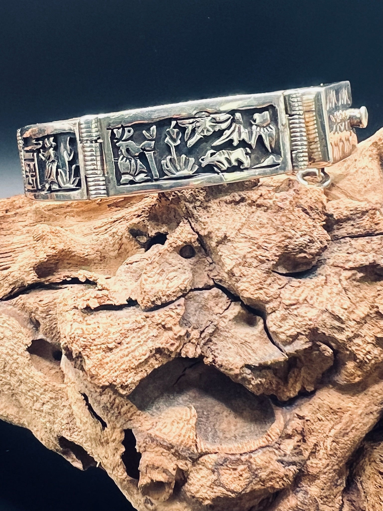 Sterling silver panel bracelet depictig a farmer under the sun, tending a sheep. It sits on top of a gnarled grape vine.